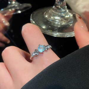 Macro view of flower leaf ring featuring a light blue round gem and sparkling zircon