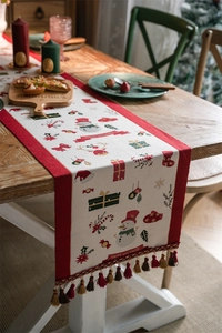 Detail of Christmas table runner with snowman patterns and colorful tassels on wood table