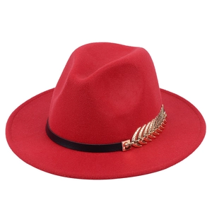 Detailed macro view of the gold leaf metal accent and black band on the red wool jazz hat