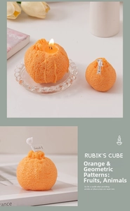 Detalle de vela aromática con forma de naranja y textura realista sobre soporte de vidrio