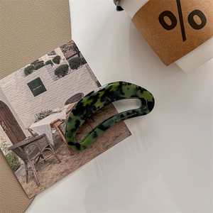 Detail of dark green tortoiseshell hair claw with gold Creation France logo on table