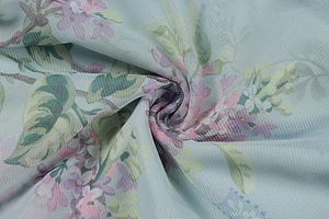 Dettaglio del tessuto mesh azzurro con stampa floreale viola e trame morbide e leggere