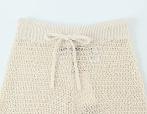Macro detail of cream knit shorts featuring an elastic drawstring waist and hollow texture