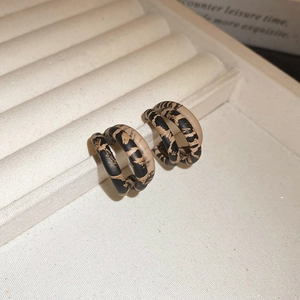 Macro detail of triple-layer leopard print hoop earrings on a white jewelry tray