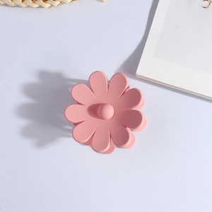 Close-up of a matte pink flower-shaped hair claw clip on a clean white surface