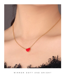 Detail of a red heart pendant necklace on a gold chain worn with black lace