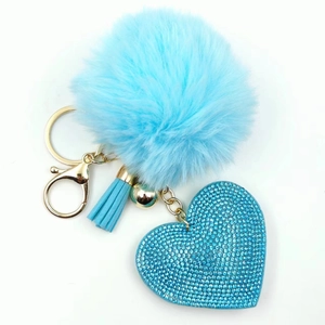 Detail of sky blue faux fur pom-pom keychain with rhinestone heart and gold tassel