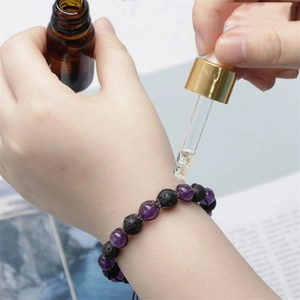 Macro view of essential oil drops on natural lava rock and amethyst energy beads