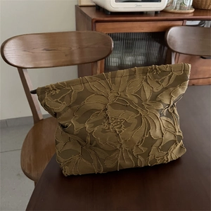 Close-up of olive brown jacquard makeup bag with intricate gold floral embroidery details