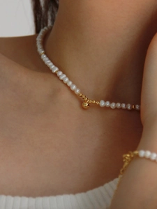Gros plan d'un collier de perles minimaliste avec perles dorées porté sur le décolleté chic