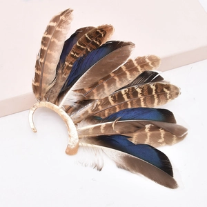 Macro detail of layered vintage peacock feathers on golden ear cuff wrap earring