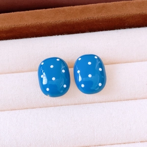 Detail of vintage blue oval earrings with white polka dots on a ribbed jewelry tray