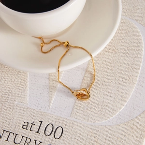 Gold-plated stainless steel double heart bracelet with cubic zirconia on a white cup