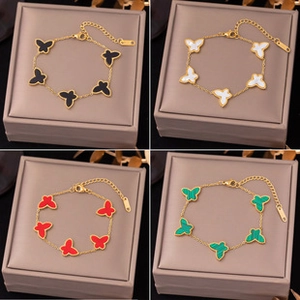 Detailed close-up of butterfly charms in black, white, red, and green on gold bracelets