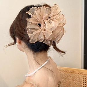 Détail d'une grande pince à cheveux avec nœud en organza champagne sur un chignon