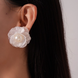 Close-up of white lace flower earring with a pearl center on a model's ear