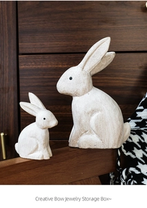 Detail of creative vintage white bunny jewelry storage box with bow on wood surface