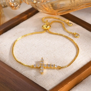 Detail of gold box chain bracelet with sparkling cross pendant on a jewelry tray