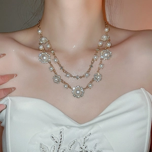Close-up of double-layer gold necklace featuring pearls and sparkling sunflower rhinestones
