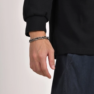 Detailed close-up of a men's vintage twisted silver metal bangle with a braided pattern