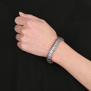 Close-up of a silver stainless steel Cuban chain bracelet worn on a male model's wrist