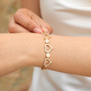 Detailed view of a gold heart-shaped bracelet with cubic zirconia on a wrist
