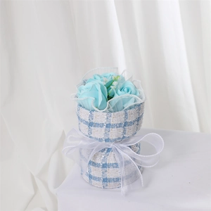 Detail of soap rose bouquet wrapped in blue tweed fabric with a white ribbon bow