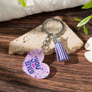 Purple heart acrylic keychain with Love You slogan and matching tassel on a rustic stone