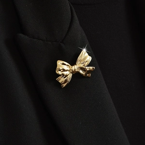 Elegant gold bow brooch pinned on black blazer fabric with sparkling light effect