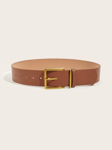 Dettaglio di una cintura in pelle marrone con fibbia quadrata dorata su uno sfondo beige