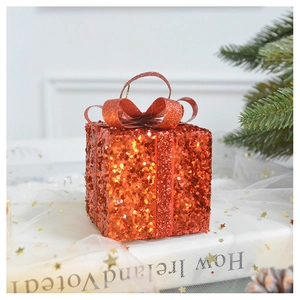 Detailed view of a red sequin gift box ornament with glitter and ribbon for Christmas