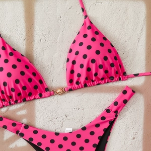 Detailed macro view of hot pink polka dot bikini with gold sun buckle on fabric