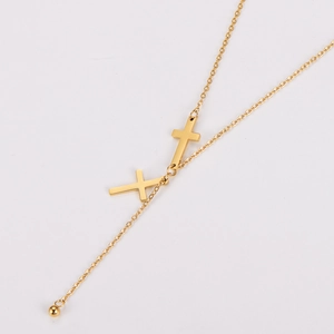 Detail of golden stainless steel necklace with double cross pendants and tassel bead