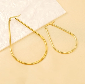 Close-up of golden teardrop hoop earrings with polished surface in two sizes