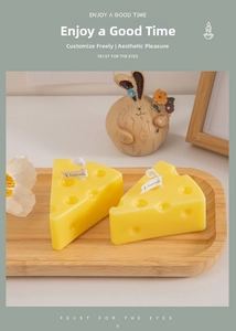 Detail view of two realistic yellow cheese-shaped scented candles with white wicks