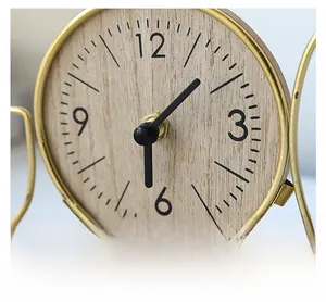Detail of modern iron clock with gold frame and wooden dial featuring metallic hands