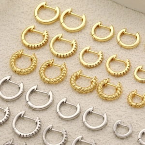 Makroaufnahme von 18K Gold- und Silber-Creolen mit Zirkonia auf einem strukturierten Display