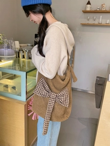 Brown teddy fleece tote bag with houndstooth bow detail carried by a model