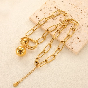Detailed macro view of golden paperclip chain necklace with round ball pendants on stone