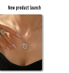 Detail of silver spiral necklace and ring set on model with minimalist modern design