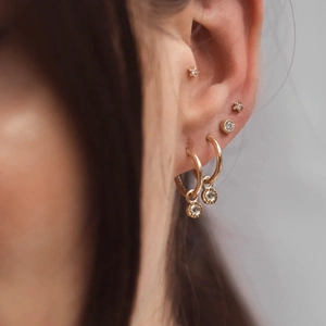 Macro shot of gold plated ear set with stars, round crystals, and zircon hoop earrings