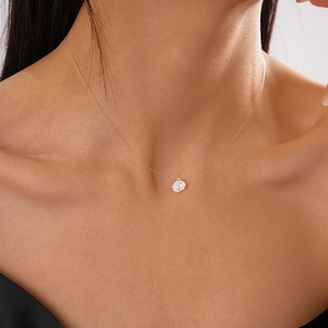Close-up of floating cubic zirconia pendant on transparent line around woman's neck