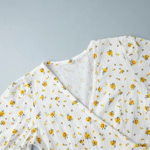 Gros plan sur la texture en coton de la robe fleurie avec col en V et imprimé de fleurs jaunes