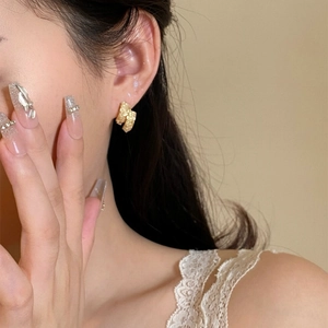 Gros plan d'élégantes boucles d'oreilles créoles texturées plaquées or 14 carats chic