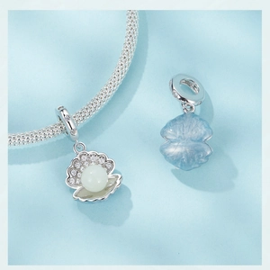 Détail de breloques en argent S925 avec perle blanche et motifs émaillés bleu clair
