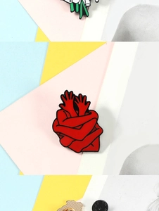 Macro shot of a red heart-shaped enamel pin with crossed arms on a colorful background