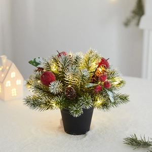 Mini Christmas pine tree with LED lights and pine cones on snowy tabletop