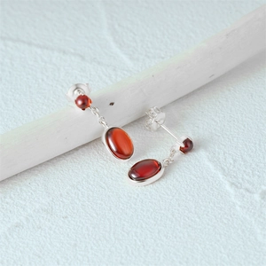 Detailed view of vintage S925 silver earrings with ruby gemstones on white wood