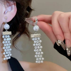 Close-up of pearl and crystal tassel clip-on earrings with elegant silver metal detail
