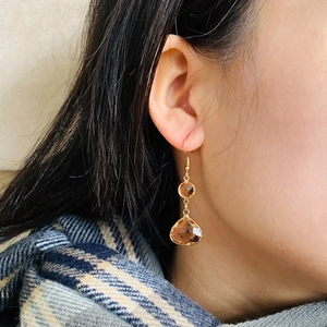 Close-up of elegant gold earrings with amber faceted teardrop crystals on a female model